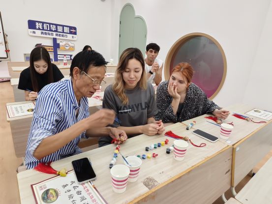 1727587637956221.jpg 图2 老师教留学生绘制菱画.jpg